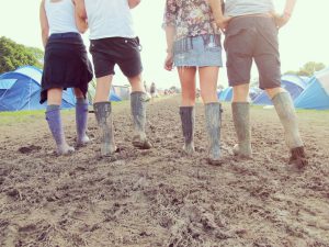Close up of friends walking through a muddy campground